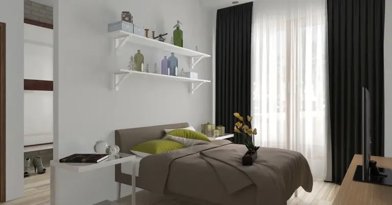 Modern bedroom with a neatly made bed and neutral bedding, featuring breathable fabrics and light-filled curtains to minimize irritants and create a calm, allergen-friendly sleeping environment.