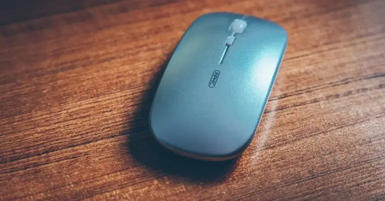 Blue wireless computer mouse resting on a wooden desk