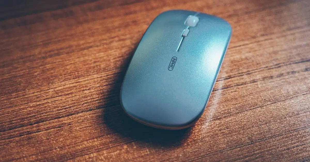 Blue wireless computer mouse resting on a wooden desk