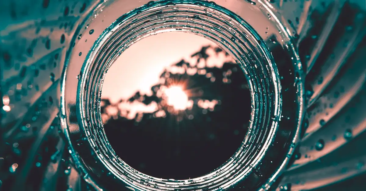 A close-up view of a water bottle with droplets and sunlight