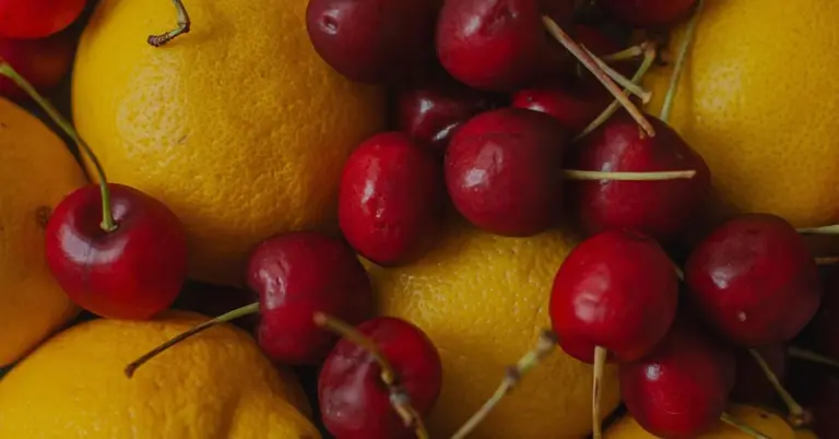 Close-up of bright yellow lemons and red cherries