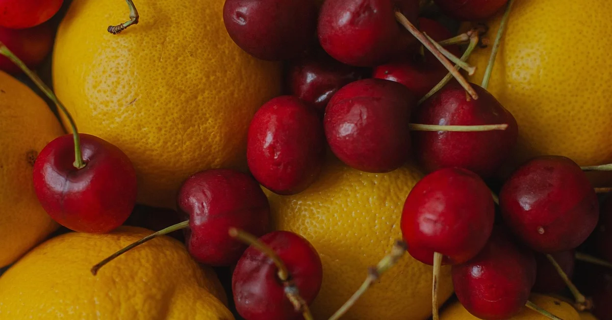Close-up of bright yellow lemons and red cherries