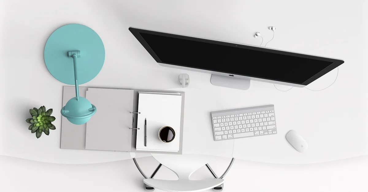 A minimalist desk setup featuring a turquoise lamp, a computer screen, and a keyboard.