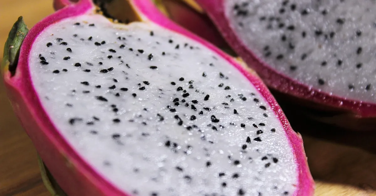 Close-up of a sliced dragon fruit showing the white flesh with black seeds.