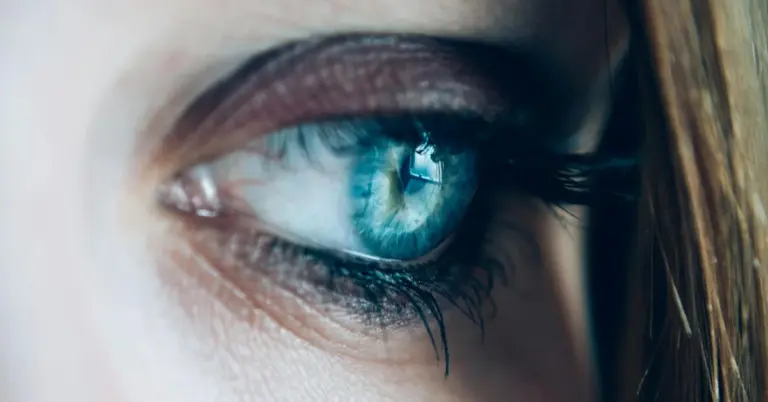 Macro image of a blue eye with long eyelashes, illustrating irritation and potential signs of conjunctivitis.