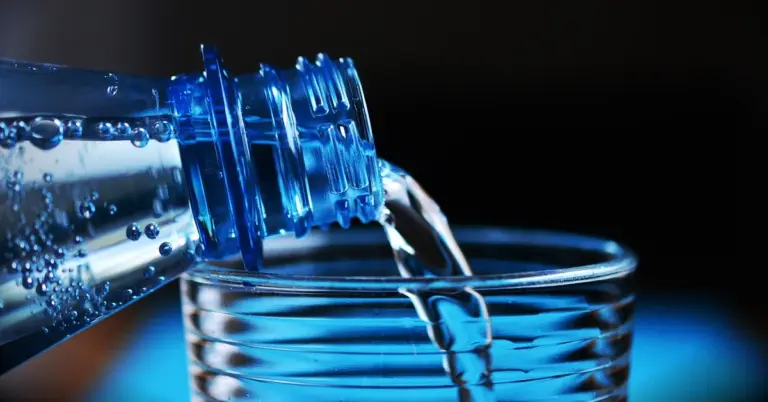 A bottle pouring fresh water into a glass