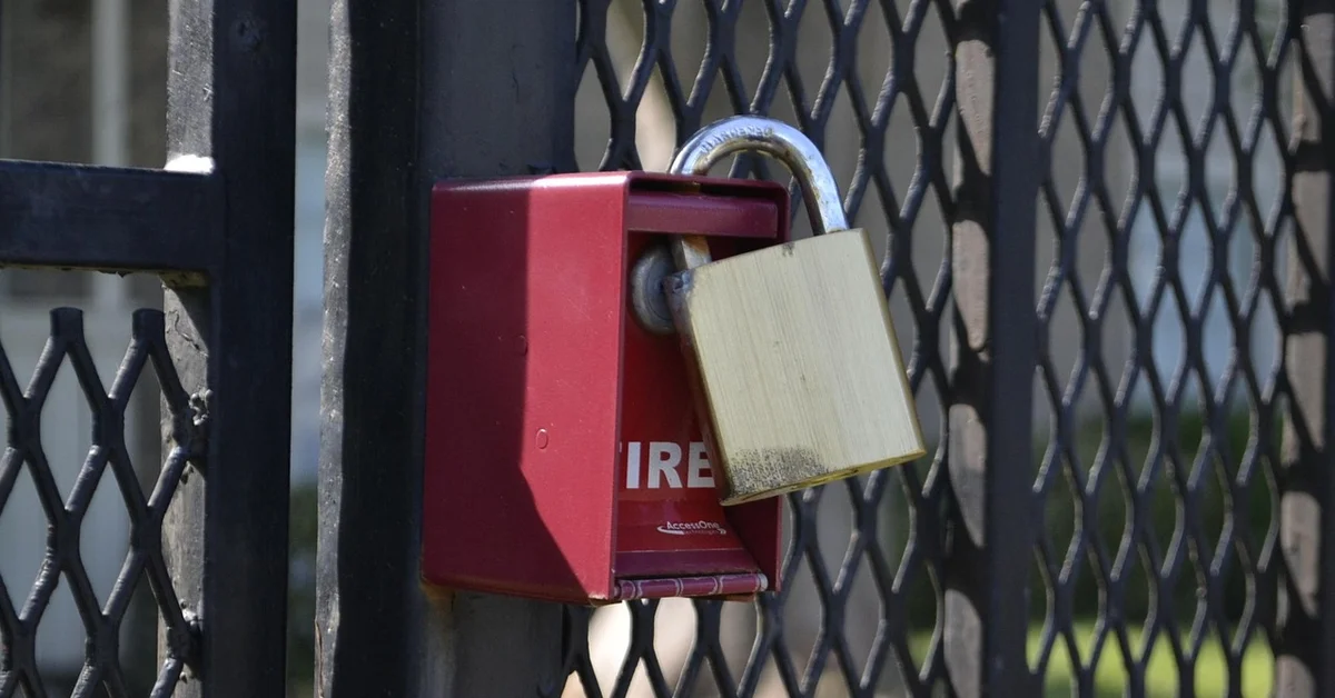 Padlock securing a gate on a metal fence, illustrating how locking entry points helps keep rodents out of an RV.