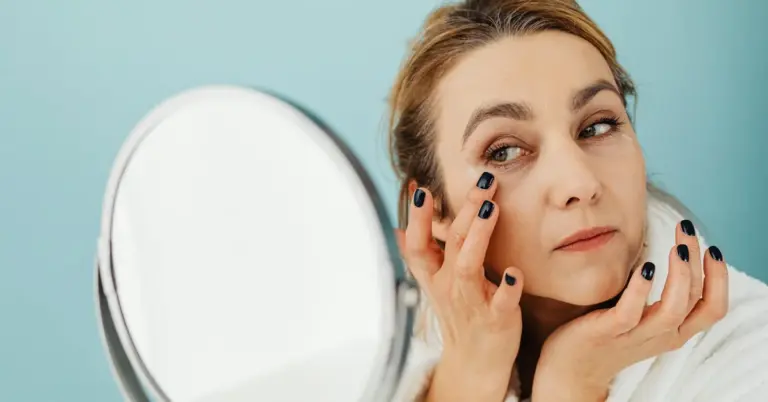 A woman applying skincare in front of a mirror, emphasizing self-care and grooming.