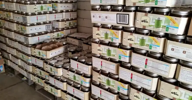 Stacks of Kerr canning jars on shelves in a warehouse.
