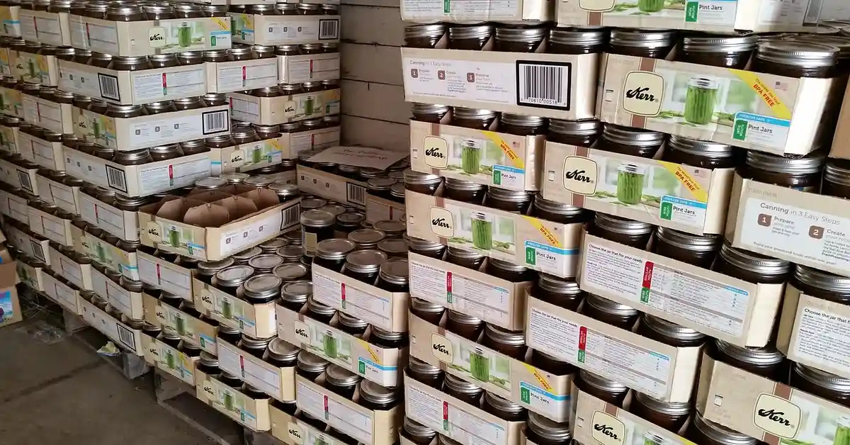 Stacks of Kerr canning jars on shelves in a warehouse.