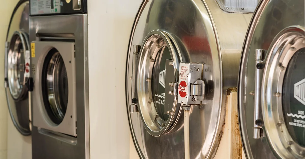 Row of stainless steel front-loading dryers in a laundromat