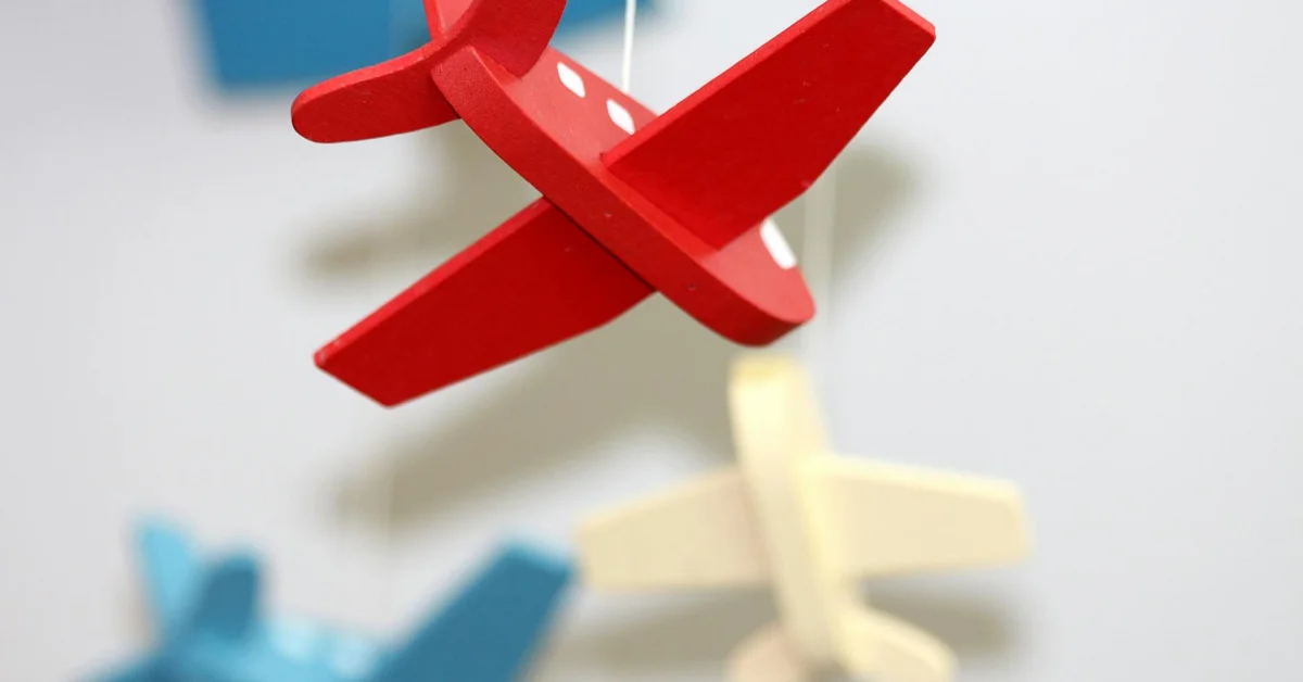 Close-up of colorful wooden DIY foraging puzzle pieces, including a red interlocking piece, with a blurred background.