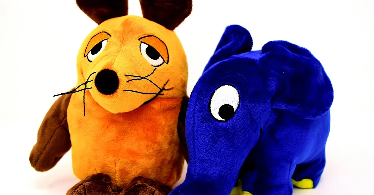 Two plush toys—a yellow-orange cat and a blue elephant—sit close together on a white background, illustrating friendly play and social interaction.