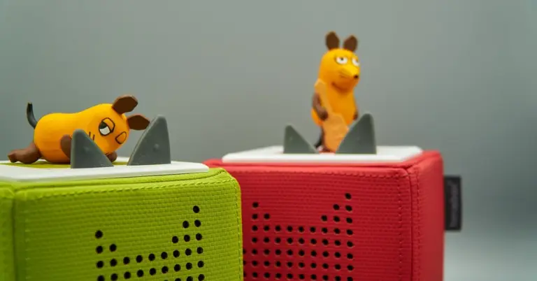 Two colorful fabric-covered play blocks (green and red) with small orange mouse figures on top and gray obstacle pieces, set against a neutral background.