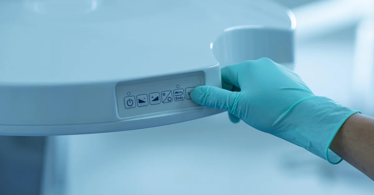 Gloved hand adjusting a control panel on an anesthesia/monitoring machine
