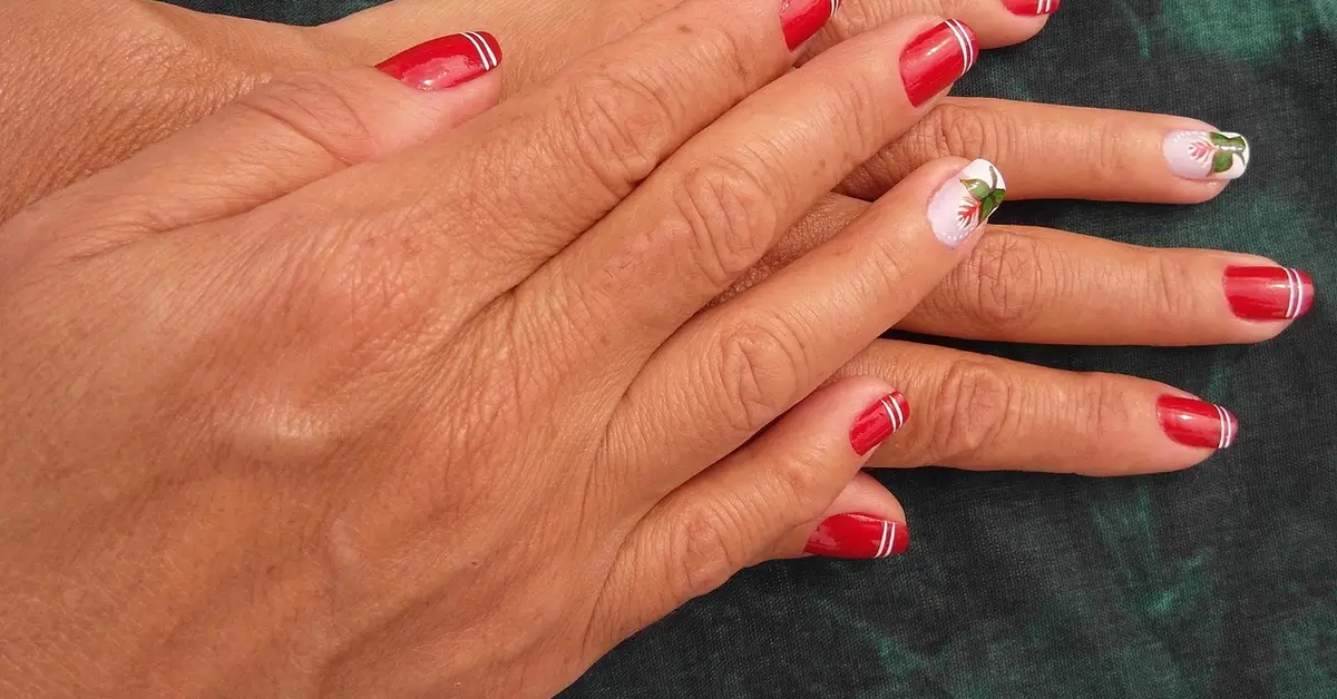 Close-up of well-manicured hands with red nails and floral designs