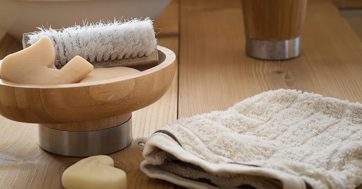 Cleaning tools on a wooden counter, including a brush in a wooden bowl, soap, and a towel, highlighting kitchen hygiene practices to prevent Salmonella.