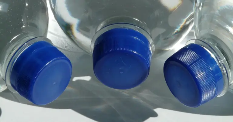 Three glass water bottles with blue screw caps viewed from below, illustrating different water delivery options.