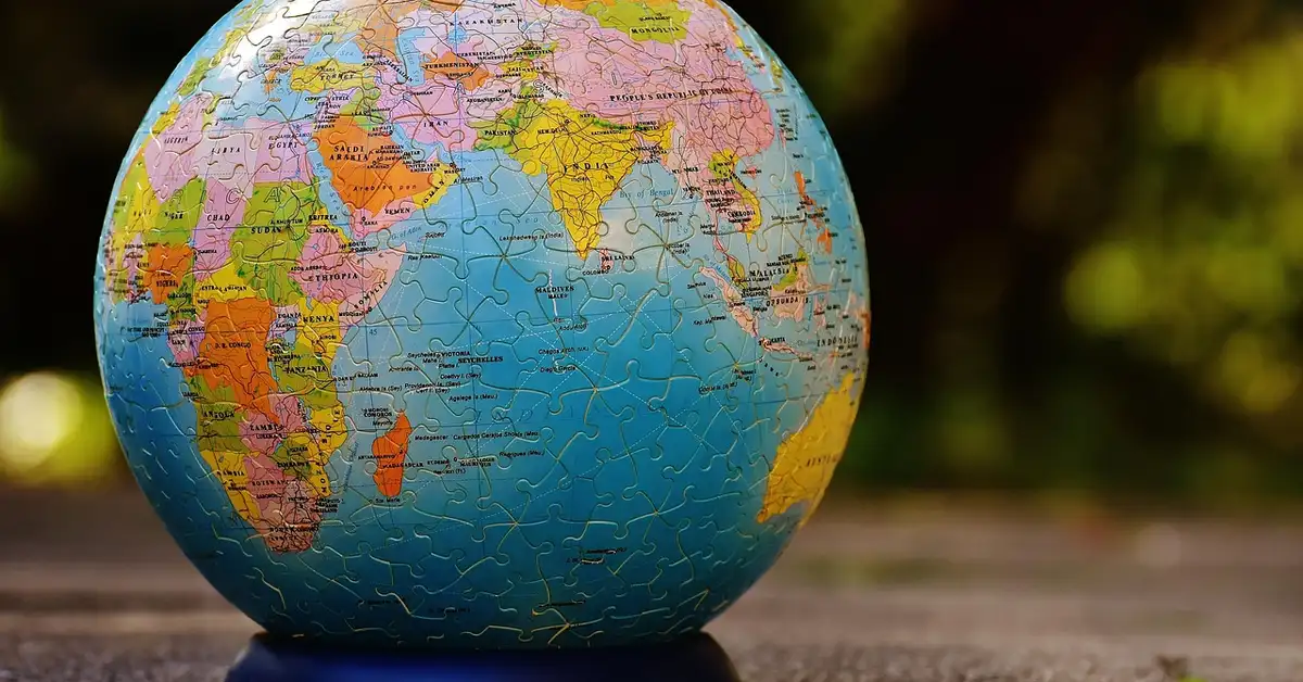 Close-up of a colorful globe-shaped jigsaw puzzle resting on a wooden surface outdoors.